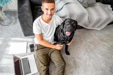 serbest meslek sahibi adam evde oturan bir kucaklama, bir köpek ile çalışan siyah labrador.