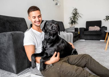 serbest meslek sahibi adam evde oturan bir kucaklama, bir köpek ile çalışan siyah labrador.