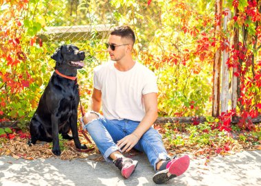 adam bir köpek ile bir parkta sonbaharda yürür.