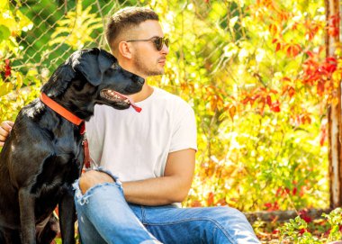 adam bir köpek ile bir parkta sonbaharda yürür.