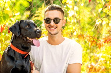 adam bir köpek ile bir parkta sonbaharda yürür.