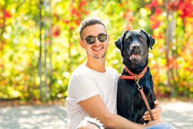 adam bir köpek ile bir parkta sonbaharda yürür.