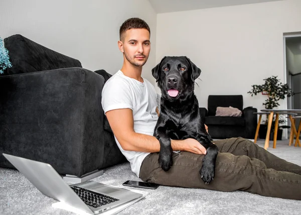 Freelancer Guy Sitting Home Working Dog Embrace Black Labrador — Stock Photo, Image