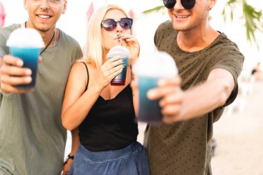 üç arkadaş neşeli şirket kalan bir tropikal plaj ve içki kokteylleri, çok, dergi kavramı