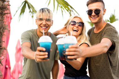 üç arkadaş neşeli şirket kalan bir tropikal plaj ve içki kokteylleri, çok, dergi kavramı