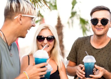 üç arkadaş neşeli şirket kalan bir tropikal plaj ve içki kokteylleri, çok, dergi kavramı