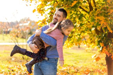 Baba ve kızı sonbahar parkta oynamak gülüyor