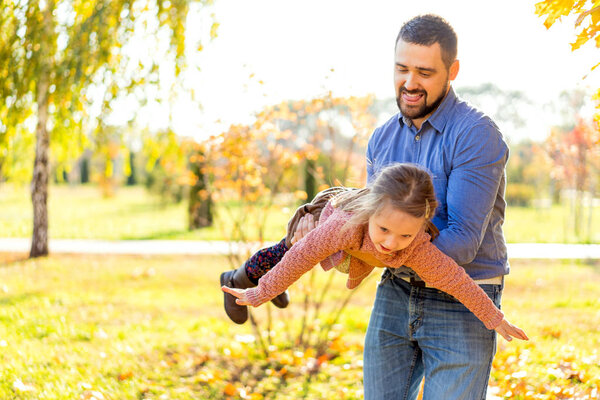 Dad and daughter in the autumn park play laughing