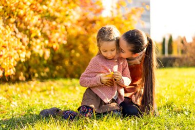 Anne ve kızı sonbahar parkta oynarken