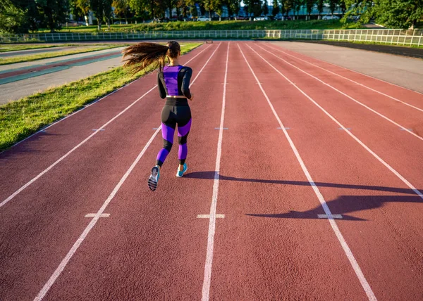 女孩运动员在日落时在体育场跑步 — 图库照片