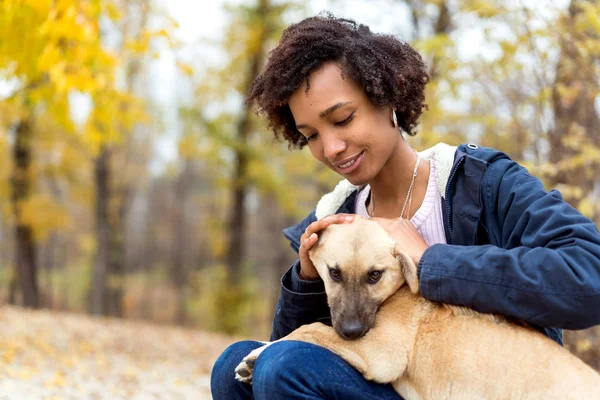非洲裔美国人的女孩在秋天的公园玩她的狗 — 图库照片
