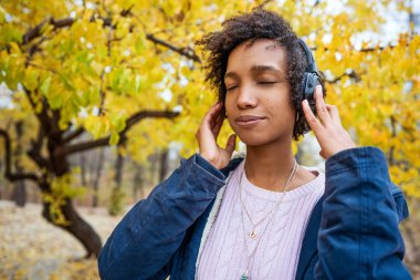 Gün batımında sonbaharda müzik Afroamerican kız