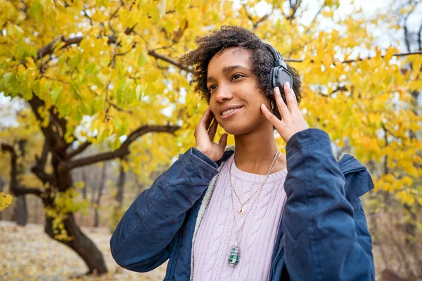 Menina afro-americana ouvindo música no outono ao pôr do sol — Fotografia de Stock