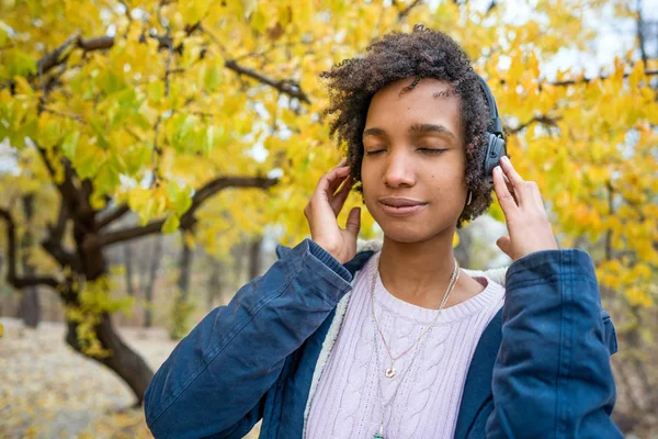 Menina afro-americana ouvindo música no outono ao pôr do sol — Fotografia de Stock