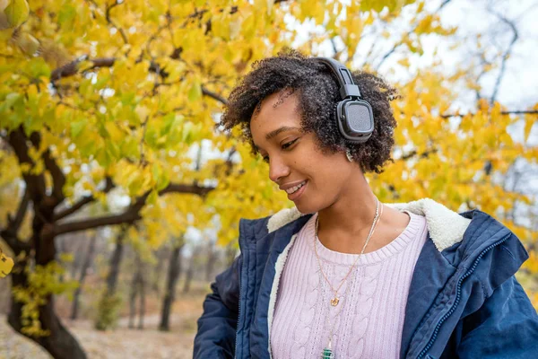 Menina afro-americana ouvindo música no outono ao pôr do sol — Fotografia de Stock