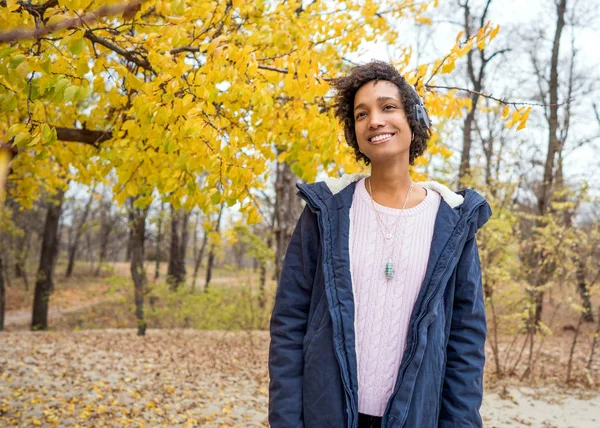 Menina afro-americana ouvindo música no outono ao pôr do sol — Fotografia de Stock