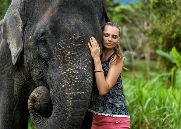 Flicka som kramar en elefant i djungeln — Stockfoto