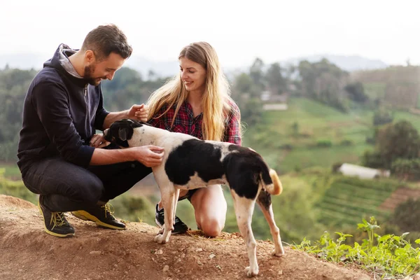 Casal apaixonado por um cão nas montanhas — Fotografia de Stock