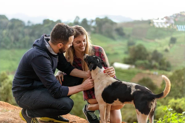 Casal apaixonado por um cão nas montanhas — Fotografia de Stock