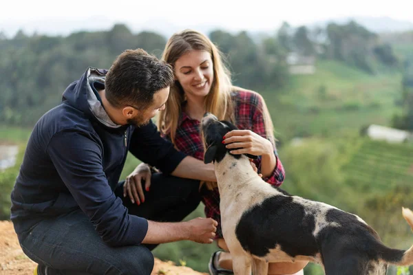 Casal apaixonado por um cão nas montanhas — Fotografia de Stock