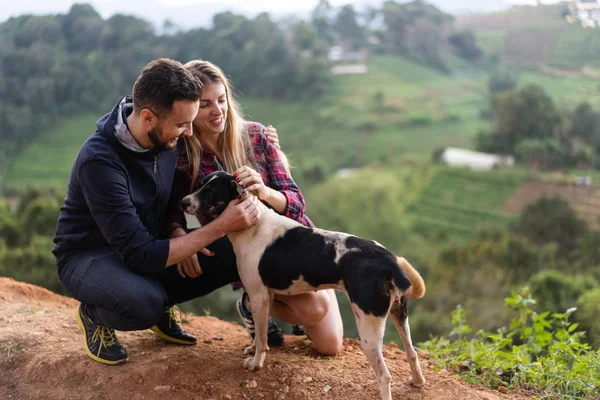 Casal apaixonado por um cão nas montanhas — Fotografia de Stock