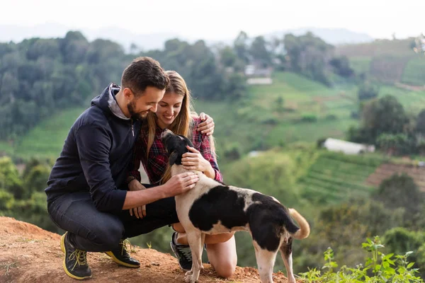 Casal apaixonado por um cão nas montanhas — Fotografia de Stock