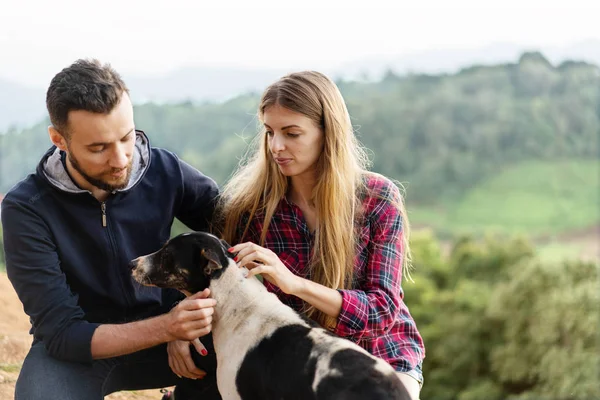 Casal apaixonado por um cão nas montanhas — Fotografia de Stock