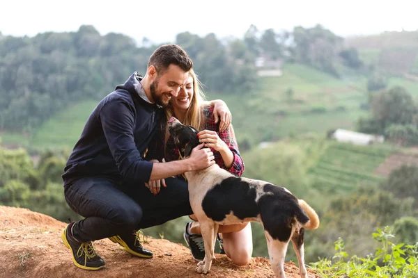 Casal apaixonado por um cão nas montanhas — Fotografia de Stock