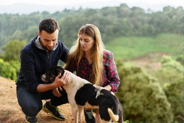 Casal apaixonado por um cão nas montanhas — Fotografia de Stock