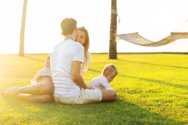 Família feliz na ilha tropical ao pôr do sol brincando com o filho — Fotografia de Stock