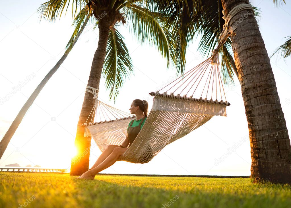 girl in a hammock bother palm trees enjoying a tropical vacation