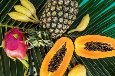 tropikal meyveler havuz yakınında palmiye yaprakları üzerinde yatıyor