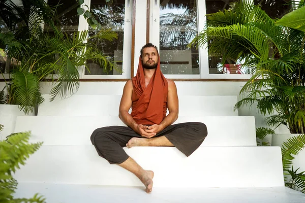 Guy gör yoga i djungeln vid solnedgången i designerkläder — Stockfoto