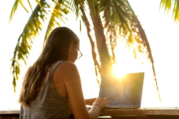 Dívka na volné noze pracující na moři při západu slunce s počítačem — Stock fotografie