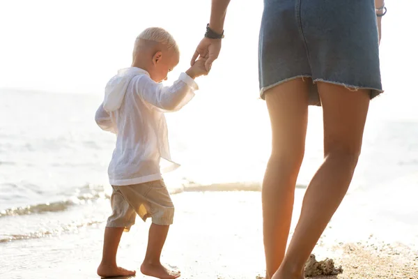 Madre jugando con su hijo al atardecer en una playa tropical — Foto de Stock