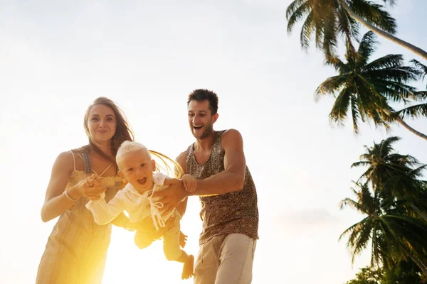 Família apaixonada na praia com o filho estão brincando ao sol — Fotografia de Stock