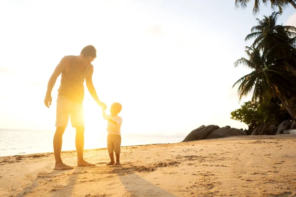 Μπαμπάς και γιος παίζουν στην άμμο στην παραλία το ηλιοβασίλεμα — Φωτογραφία Αρχείου