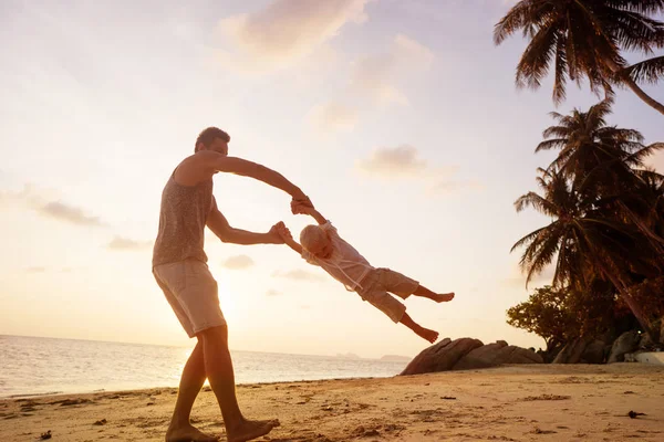 Pai e filho brincando na areia na praia ao pôr do sol — Fotografia de Stock