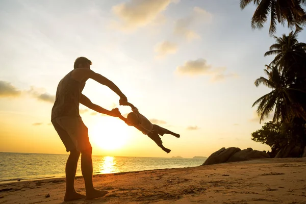 Dad and son playing on the sand at the beach at sunset — Stock Photo, Image