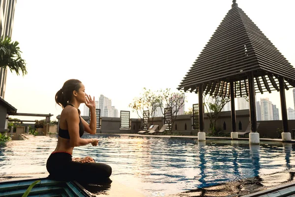 Flickan mediterar vid solnedgången i Thailand nära poolen — Stockfoto