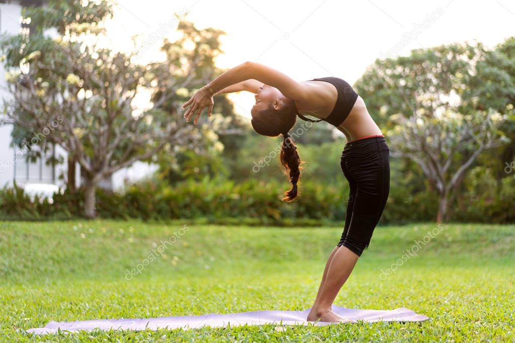 girl doing yoga at sunset in Thailand in the park