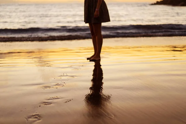 Jambes de fille au coucher du soleil sur la plage — Photo