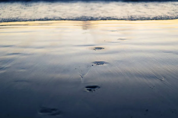 Zwart zand bij zonsondergang, voetafdrukken in het zand — Stockfoto