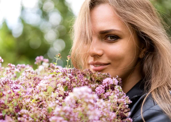 Retrato de una hermosa chica de moda con un ramo de flores lila en la calle — Foto de Stock