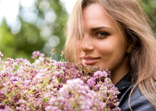 Porträt einer schönen Mode-Mädchen mit einem Strauß fliederfarbener Blumen auf der Straße — Stockfoto