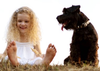 bir köpek ile küçük kız gün batımında parkta oynar