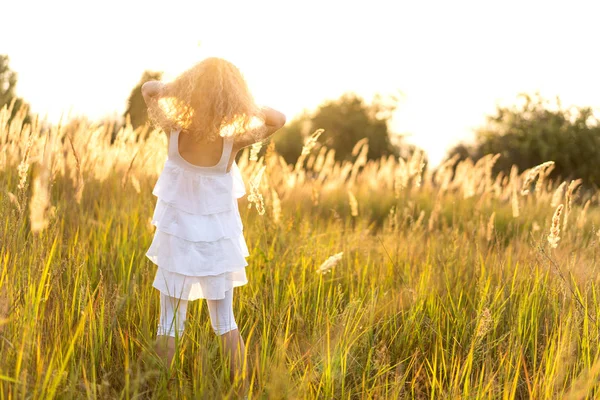 夕焼けの小さな女の子が野原で遊ぶ — ストック写真