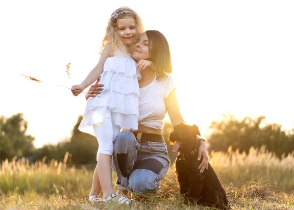 Mor med dotter med hund miniatyr Schnauzer spelar vid solnedgången — Stockfoto