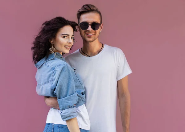 Casal de moda em óculos de sol posando na parede rosa — Fotografia de Stock