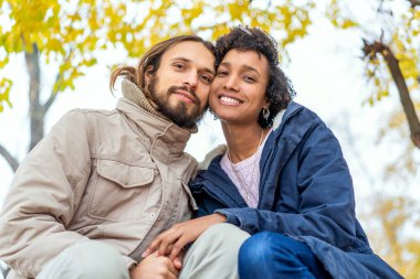 Sonbahar parkında aşık Afrikalı Amerikalı bir kızla gün batımında yürüyüşe çıkan bir adam.